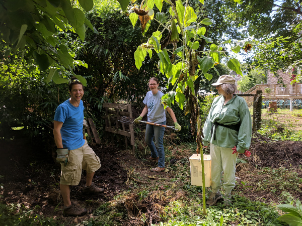 photo: three people gathered around compost pile