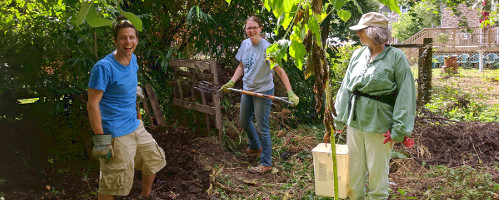 Three people laughing near compost bin