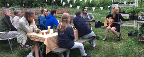 photo: people seated at picnic table listening to musicians