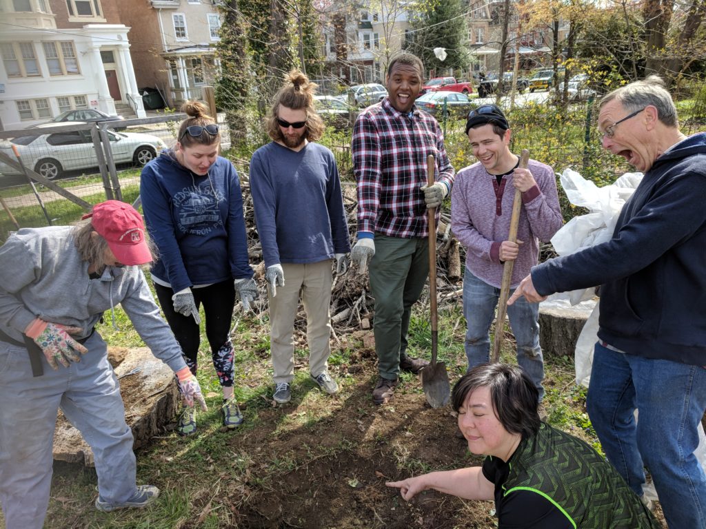 photo: a group of people with shovels point at hole in the ground