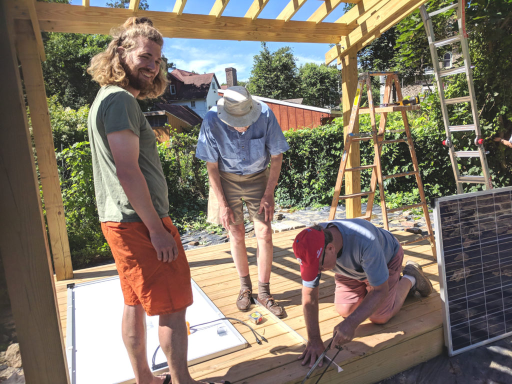 photo: Three people working to install solar panels