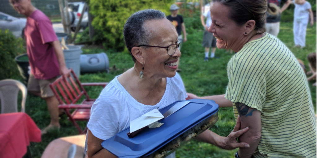 photo: Two people laughing with covered dish