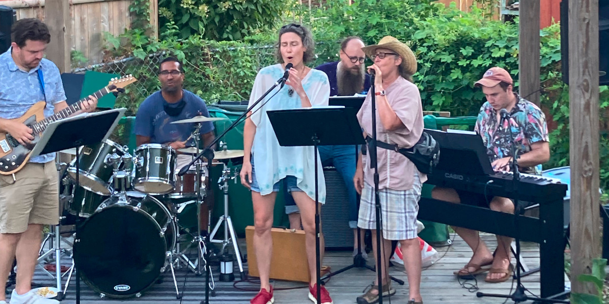 photo of band playing outdoors with two singers